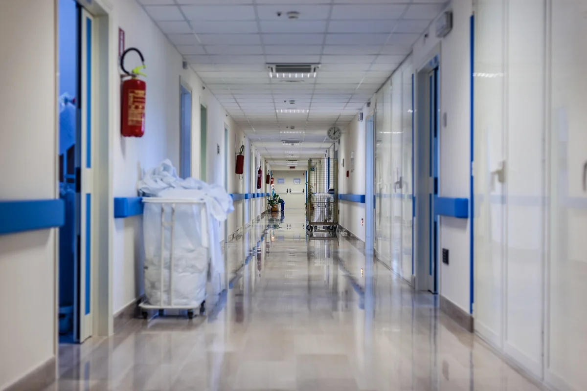 Corridoio di reparto ospedaliero pulito e luminoso, con pavimento lucido e carrello della biancheria
